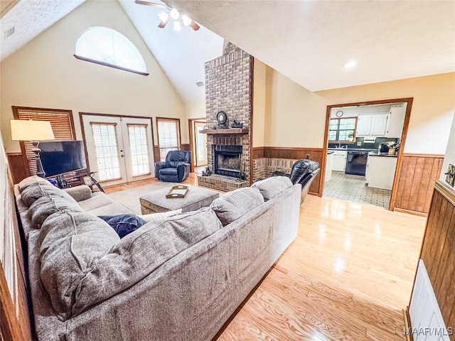 1267 County Road 85th Rd, Prattville, AL 36067 - living room featuring a wainscoted wall, a fireplace, light wood-style flooring, high vaulted ceiling, and a ceiling fan