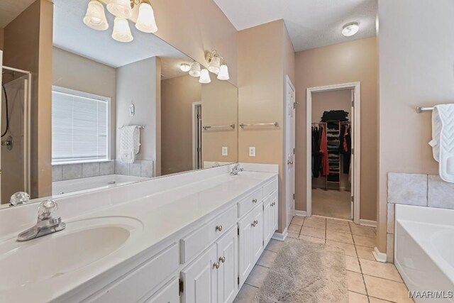 709 Liberty Rd, Tallassee, AL 36078 - bathroom featuring a chandelier, a bath, double vanity, tile patterned flooring, and a spacious closet