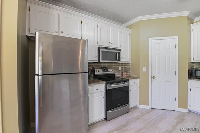 709 Liberty Rd, Tallassee, AL 36078 - kitchen featuring appliances with stainless steel finishes, white cabinets, tasteful backsplash, ornamental molding, and dark stone counters