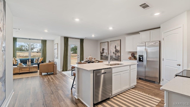 6036 Cunningham Trl, Montgomery, AL 36116 - kitchen featuring appliances with stainless steel finishes, light wood finished floors, white cabinets, an island with sink, and recessed lighting