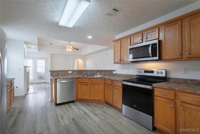 9621 Colleton Pl, Montgomery, AL 36117 - kitchen featuring stainless steel appliances, a peninsula, light wood finished floors, a textured ceiling, and a raised ceiling