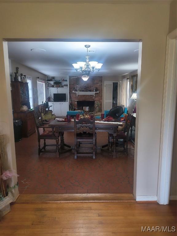 2205 Old Orrville Rd, Selma, AL 36701 - dining space featuring a chandelier, wood finished floors, and a brick fireplace