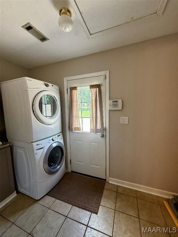 311 Old Marion Junction Rd, Selma, AL 36701 - laundry area with stacked washer / drying machine, light tile patterned flooring, and attic access