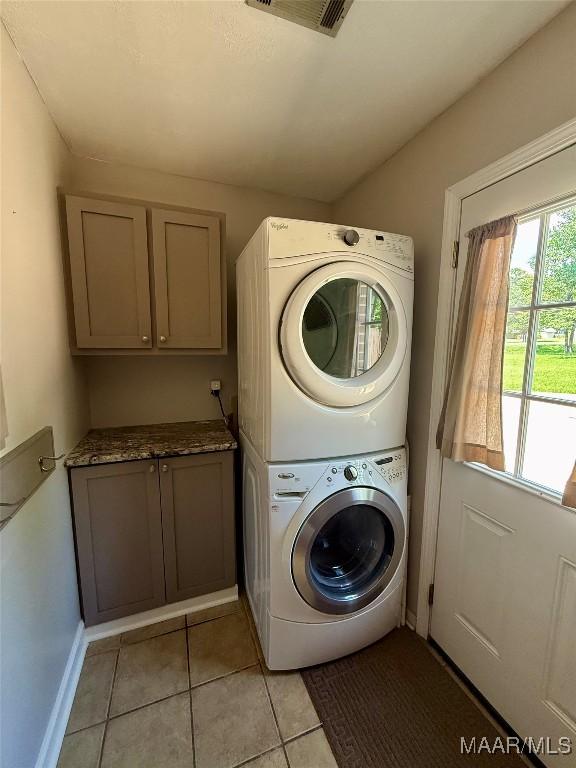 311 Old Marion Junction Rd, Selma, AL 36701 - washroom featuring stacked washer / dryer, cabinet space, and light tile patterned floors