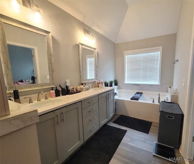 1008 Overture Dr, Montgomery, AL 36117 - bathroom featuring double vanity, a bath, wood finished floors, and lofted ceiling
