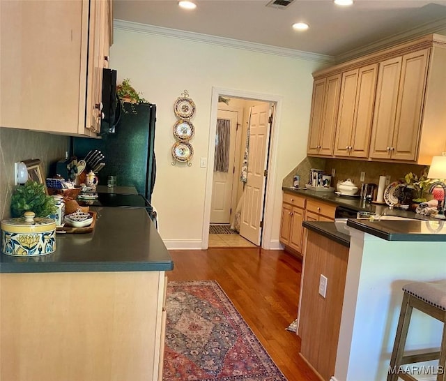 5650 Ash Grove Ct, Montgomery, AL 36116 - kitchen featuring crown molding, dark countertops, dark wood-style flooring, a kitchen bar, and a peninsula
