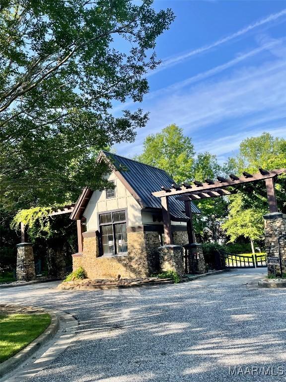5650 Ash Grove Ct, Montgomery, AL 36116 - view of front facade featuring a standing seam roof, gravel driveway, a metal roof, and stone siding