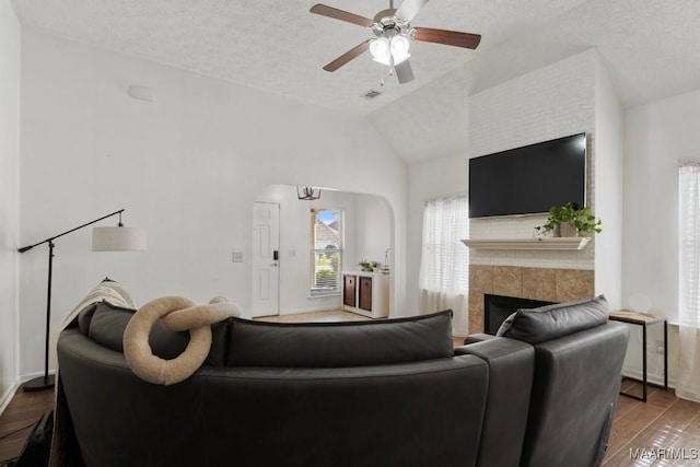 6526 Ridgeview Ln, Montgomery, AL 36116 - living area featuring wood finished floors, lofted ceiling, ceiling fan, a tile fireplace, and arched walkways