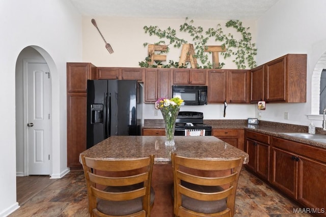 6526 Ridgeview Ln, Montgomery, AL 36116 - kitchen featuring black appliances, arched walkways, stone finish floors, and a center island
