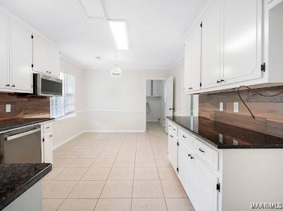 1243 Highpoint Rd, Montgomery, AL 36109 - kitchen with stainless steel appliances, backsplash, white cabinetry, and light tile patterned floors