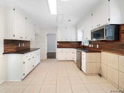 1243 Highpoint Rd, Montgomery, AL 36109 - kitchen featuring stainless steel appliances, dark countertops, decorative backsplash, light tile patterned floors, and white cabinetry