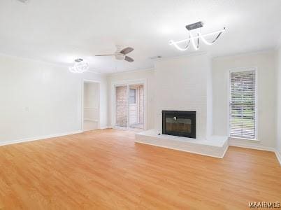 1243 Highpoint Rd, Montgomery, AL 36109 - unfurnished living room with a glass covered fireplace, light wood-style floors, ornamental molding, a ceiling fan, and a chandelier