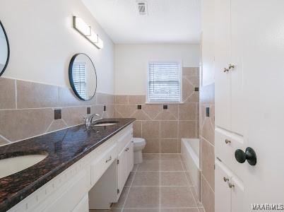 1243 Highpoint Rd, Montgomery, AL 36109 - bathroom featuring tile patterned floors, double vanity, and tile walls