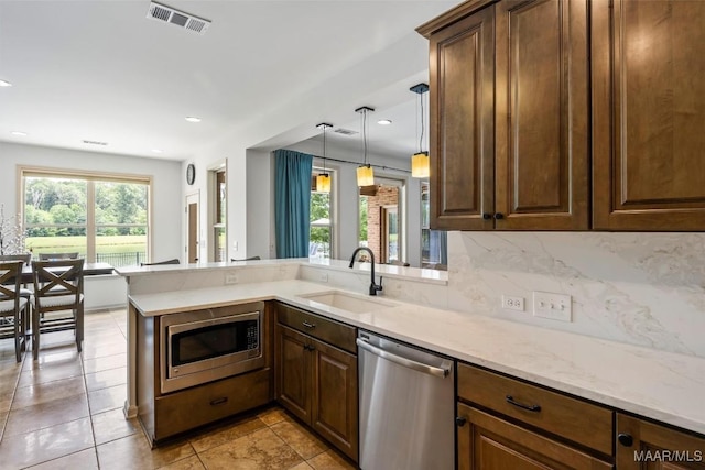 9185 Brenham Ct, Montgomery, AL 36117 - kitchen with appliances with stainless steel finishes, a peninsula, light stone counters, light tile patterned flooring, and recessed lighting