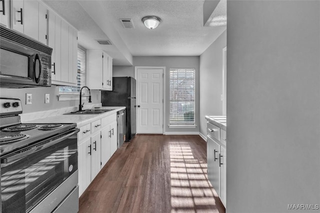 3213 Milan Dr, Montgomery, AL 36109 - kitchen featuring electric stove, black microwave, light countertops, dark wood-style floors, and a textured ceiling