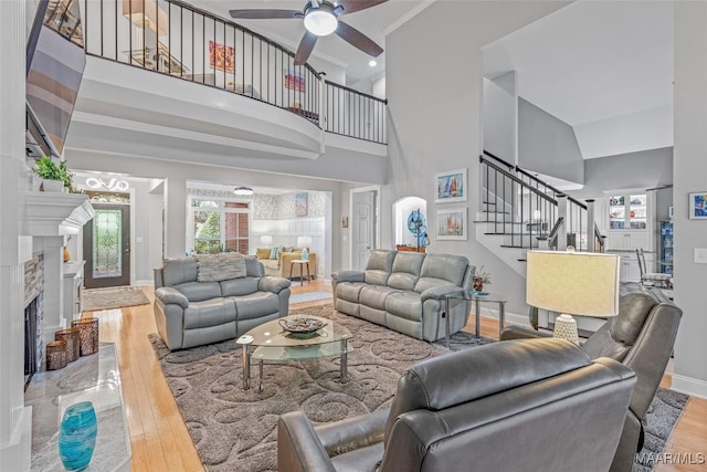 378 Winding Wood Dr, Wetumpka, AL 36093 - living area with wood finished floors, stairway, ceiling fan, a high ceiling, and a tile fireplace