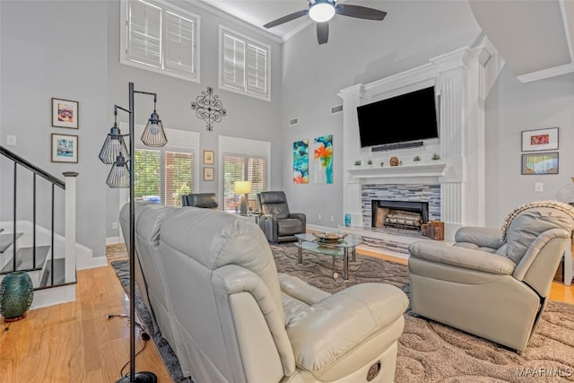 378 Winding Wood Dr, Wetumpka, AL 36093 - living area with wood finished floors, ceiling fan, a tiled fireplace, stairs, and a high ceiling