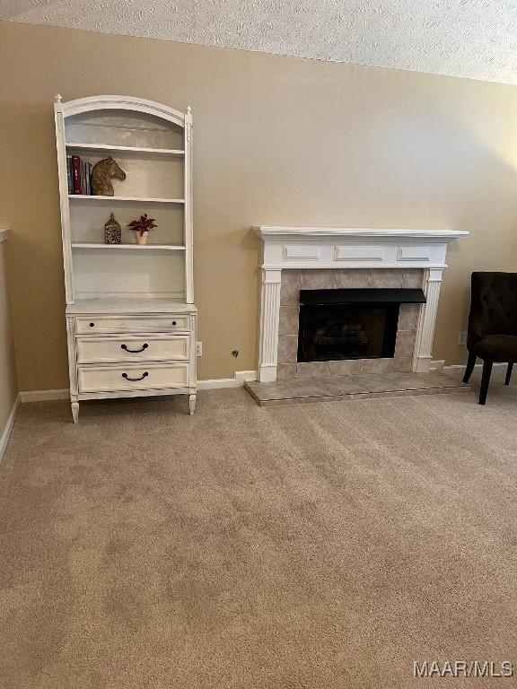 9324 Bristlecone Dr, Montgomery, AL 36117 - unfurnished living room featuring a textured ceiling, carpet, and a tiled fireplace