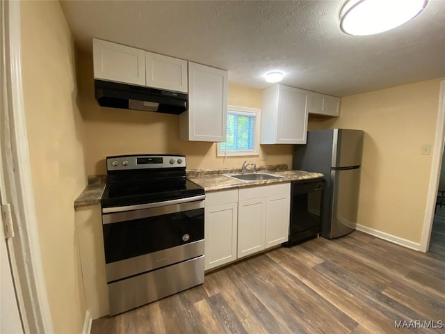 1010 New St, Tuskegee, AL 36083 - kitchen featuring stainless steel appliances, under cabinet range hood, dark wood-style floors, white cabinetry, and a textured ceiling