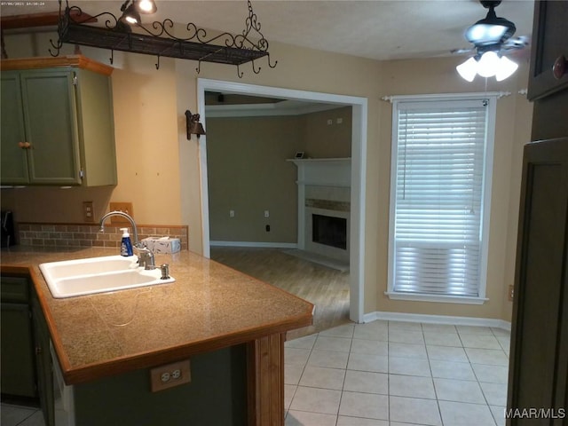 213 Foxdale Rd, Millbrook, AL 36054 - kitchen with a fireplace, a peninsula, a ceiling fan, green cabinets, and light tile patterned floors