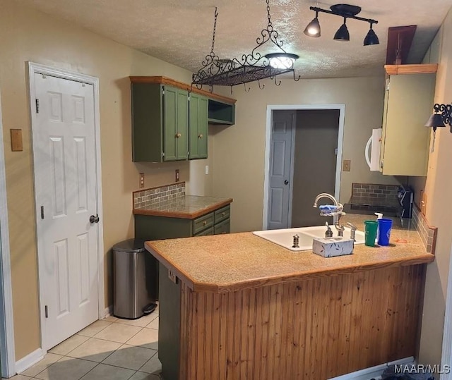 213 Foxdale Rd, Millbrook, AL 36054 - kitchen featuring green cabinetry, a peninsula, white microwave, a textured ceiling, and light tile patterned floors