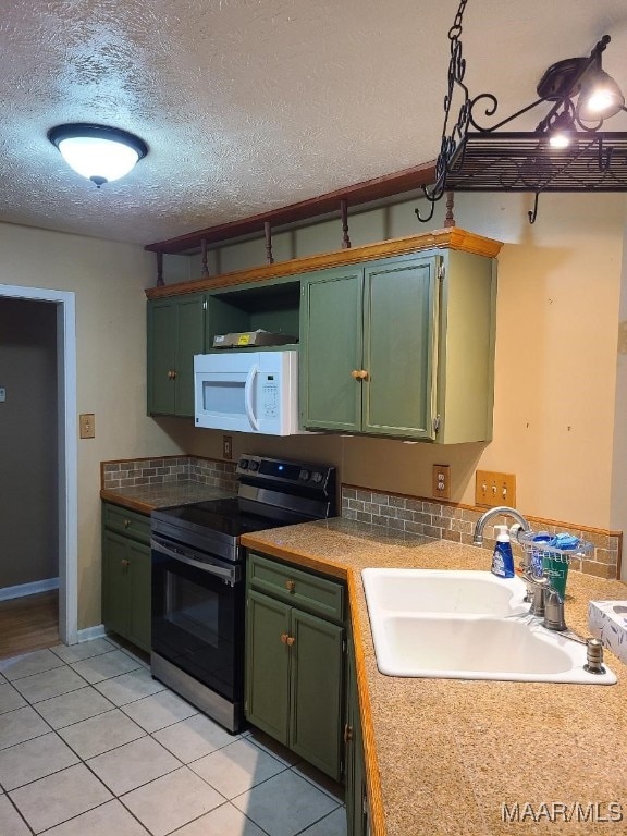 213 Foxdale Rd, Millbrook, AL 36054 - kitchen with white microwave, electric range, green cabinets, light tile patterned flooring, and light countertops