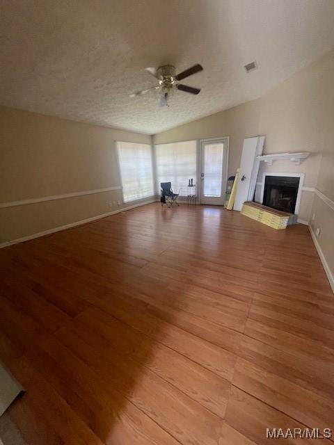 3440 Wickham Rd, Montgomery, AL 36116 - unfurnished living room with light wood-style floors, ceiling fan, a fireplace with raised hearth, and a textured ceiling