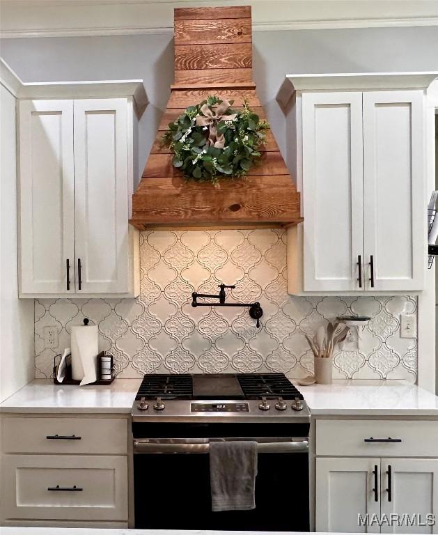 447 Cloverdale Rd, Greenville, AL 36037 - kitchen featuring stainless steel gas stove, light countertops, backsplash, white cabinetry, and ornamental molding