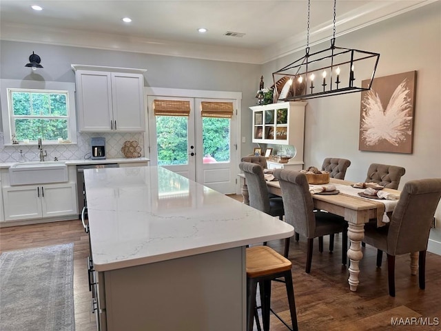 447 Cloverdale Rd, Greenville, AL 36037 - kitchen with wood finished floors, a kitchen bar, a kitchen island, french doors, and decorative backsplash