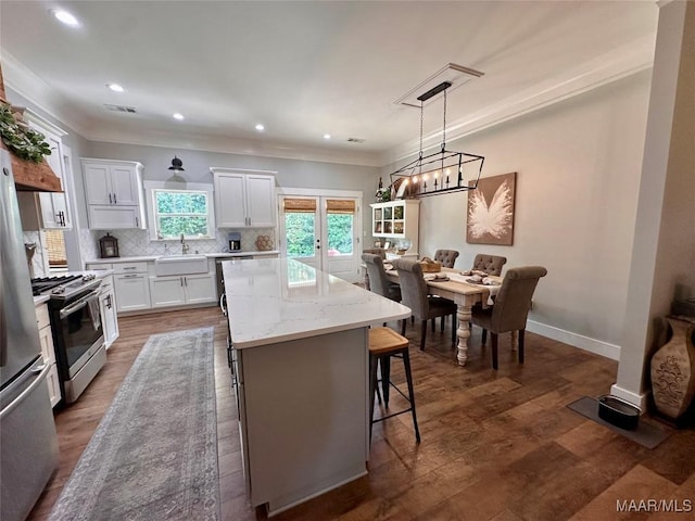447 Cloverdale Rd, Greenville, AL 36037 - kitchen with appliances with stainless steel finishes, a center island, white cabinetry, a kitchen breakfast bar, and backsplash