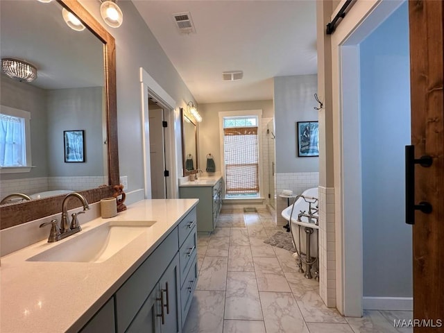 447 Cloverdale Rd, Greenville, AL 36037 - bathroom with marble look tiles, two vanities, a freestanding bath, a stall shower, and wainscoting