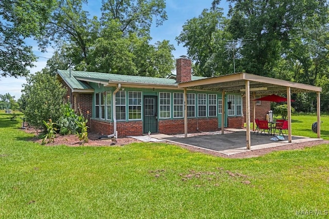 445 W Hickory Grove Rd, Lapine, AL 36046 - rear view of house featuring a patio, brick siding, a chimney, a lawn, and a metal roof