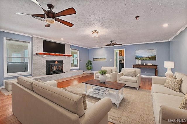 445 W Hickory Grove Rd, Lapine, AL 36046 - living area with ceiling fan, a wood stove, light wood finished floors, ornamental molding, and a textured ceiling