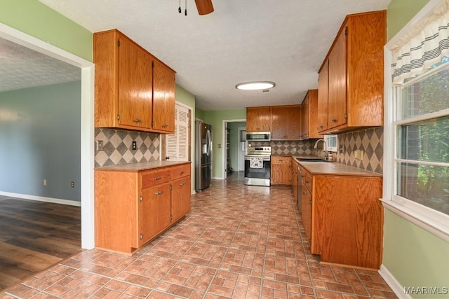 445 W Hickory Grove Rd, Lapine, AL 36046 - kitchen featuring stainless steel appliances, brown cabinetry, decorative backsplash, and a textured ceiling