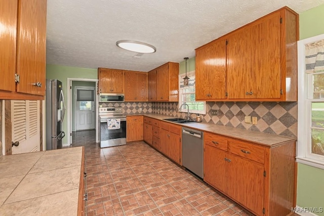 445 W Hickory Grove Rd, Lapine, AL 36046 - kitchen featuring stainless steel appliances, tile countertops, tasteful backsplash, brown cabinetry, and brick patterned flooring