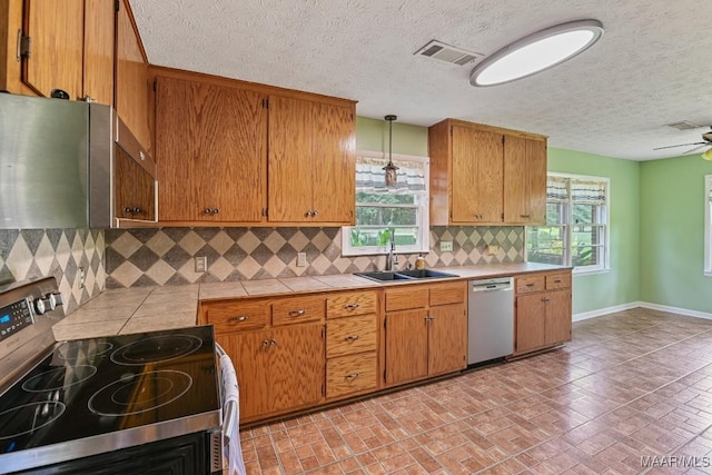 445 W Hickory Grove Rd, Lapine, AL 36046 - kitchen featuring appliances with stainless steel finishes, tile counters, plenty of natural light, brown cabinetry, and a textured ceiling