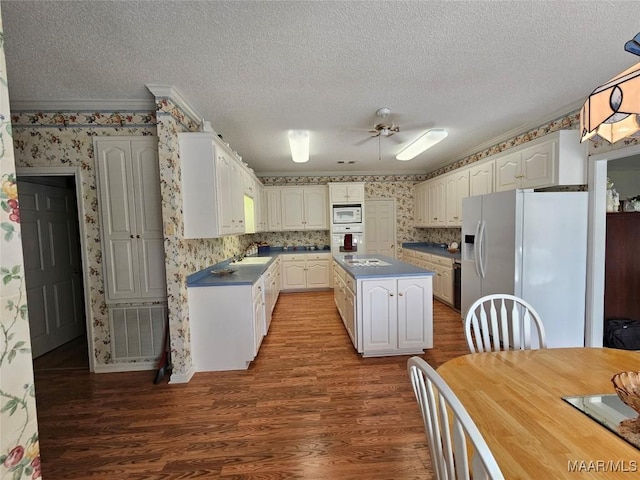 2714 Luverne Hwy, Greenville, AL 36037 - kitchen with white appliances, wallpapered walls, wood finished floors, a textured ceiling, and dark countertops