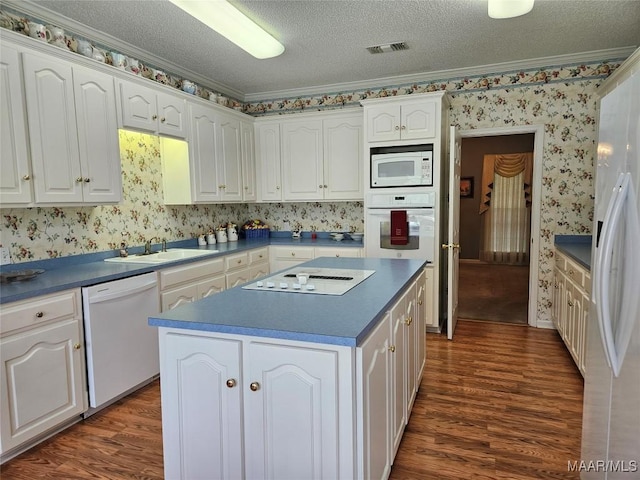 2714 Luverne Hwy, Greenville, AL 36037 - kitchen with white appliances, dark wood-style flooring, a kitchen island, white cabinets, and wallpapered walls