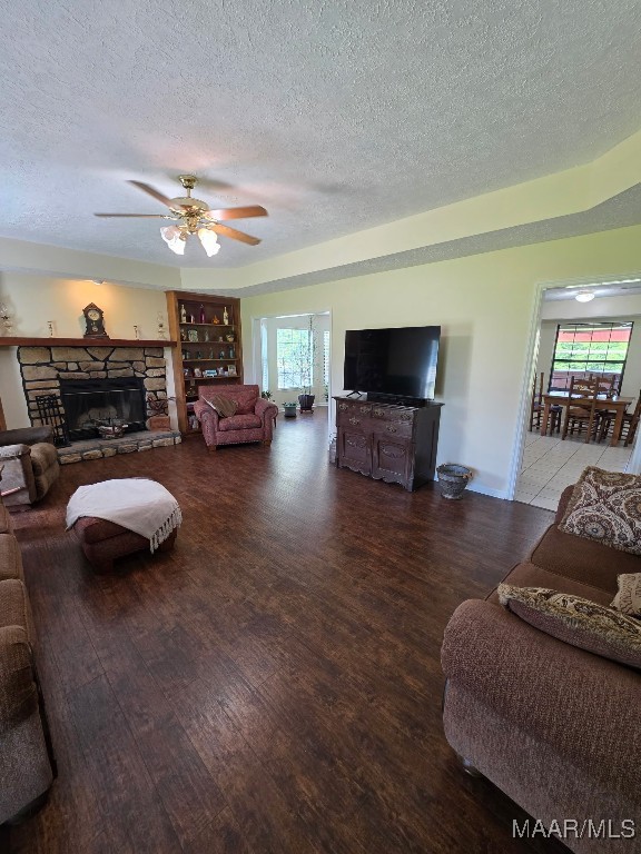 973 Pettus Rd, Lapine, AL 36046 - living area featuring a textured ceiling, wood finished floors, a stone fireplace, and a ceiling fan