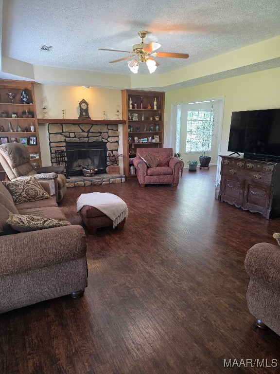 973 Pettus Rd, Lapine, AL 36046 - living area with a textured ceiling, wood finished floors, a ceiling fan, a fireplace, and built in shelves