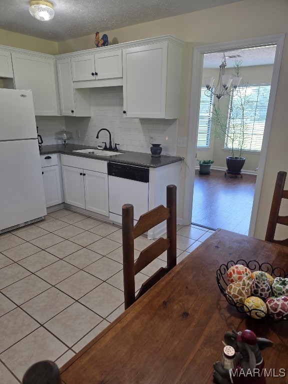 973 Pettus Rd, Lapine, AL 36046 - kitchen with white appliances, light tile patterned floors, dark countertops, white cabinets, and decorative backsplash