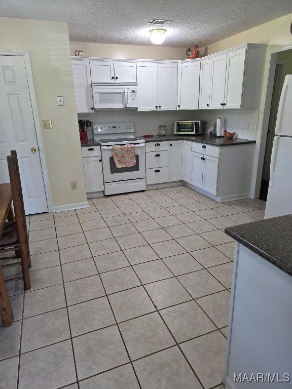 973 Pettus Rd, Lapine, AL 36046 - kitchen featuring white appliances, dark countertops, white cabinetry, a textured ceiling, and light tile patterned flooring