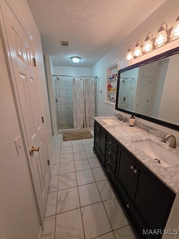 973 Pettus Rd, Lapine, AL 36046 - full bathroom featuring a textured ceiling, a stall shower, marble look tile flooring, and double vanity