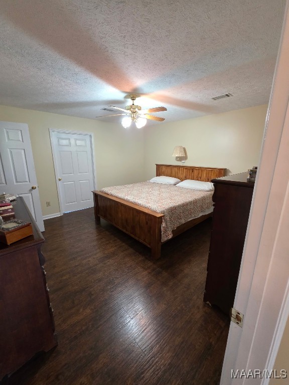 973 Pettus Rd, Lapine, AL 36046 - bedroom featuring dark wood-style flooring, a textured ceiling, and ceiling fan