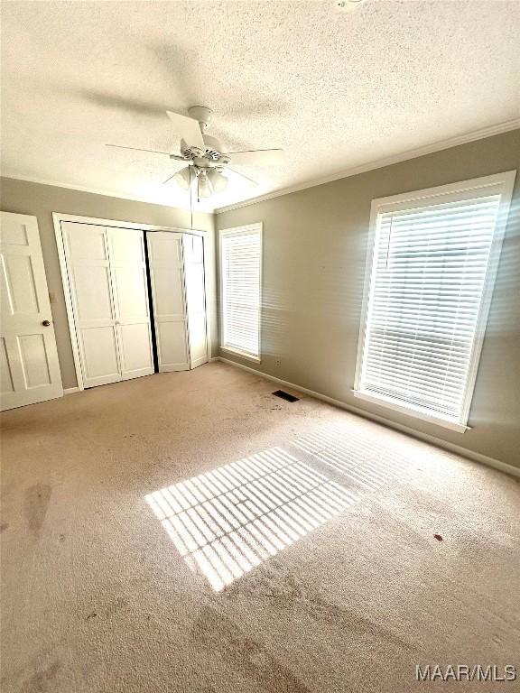 2 Rolling Hills Cir, Camden, AL 36726 - unfurnished bedroom with carpet, a textured ceiling, multiple windows, a closet, and a ceiling fan
