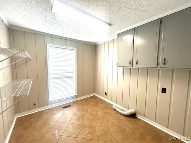 2 Rolling Hills Cir, Camden, AL 36726 - laundry area with light tile patterned floors, a decorative wall, cabinet space, and a textured ceiling
