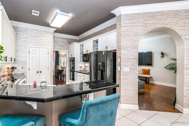 8712 Old Marsh Way, Montgomery, AL 36117 - kitchen featuring a kitchen bar, arched walkways, black appliances, light tile patterned floors, and ornamental molding