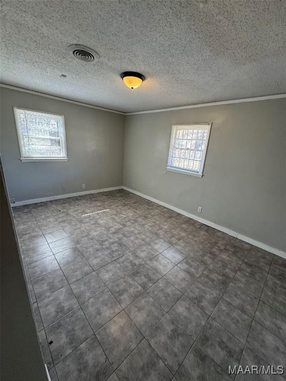 3902 Wesley Dr, Montgomery, AL 36111 - spare room with crown molding, a textured ceiling, and dark tile patterned floors