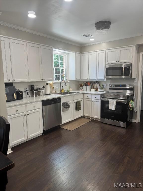 3549 Audubon Rd, Montgomery, AL 36111 - kitchen with appliances with stainless steel finishes, crown molding, light countertops, white cabinets, and dark wood-style floors