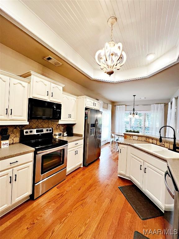 267 River Birch Cir, Wetumpka, AL 36093 - kitchen featuring stainless steel appliances, a chandelier, light wood-style flooring, white cabinets, and pendant lighting